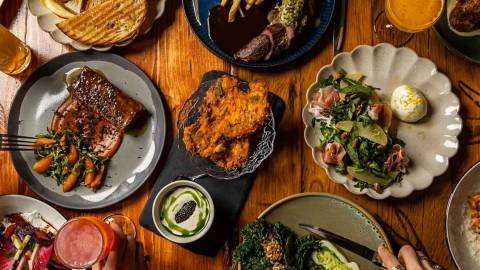 An overhead shot of a food spread - there are many plates of various foods from cold treats to salads and meats.